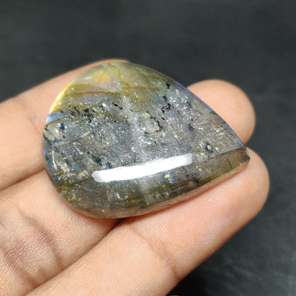 Cabochons4sale pear-shaped translucent labradorite gemstone with multi-colour iridescent flashes held in a hand.