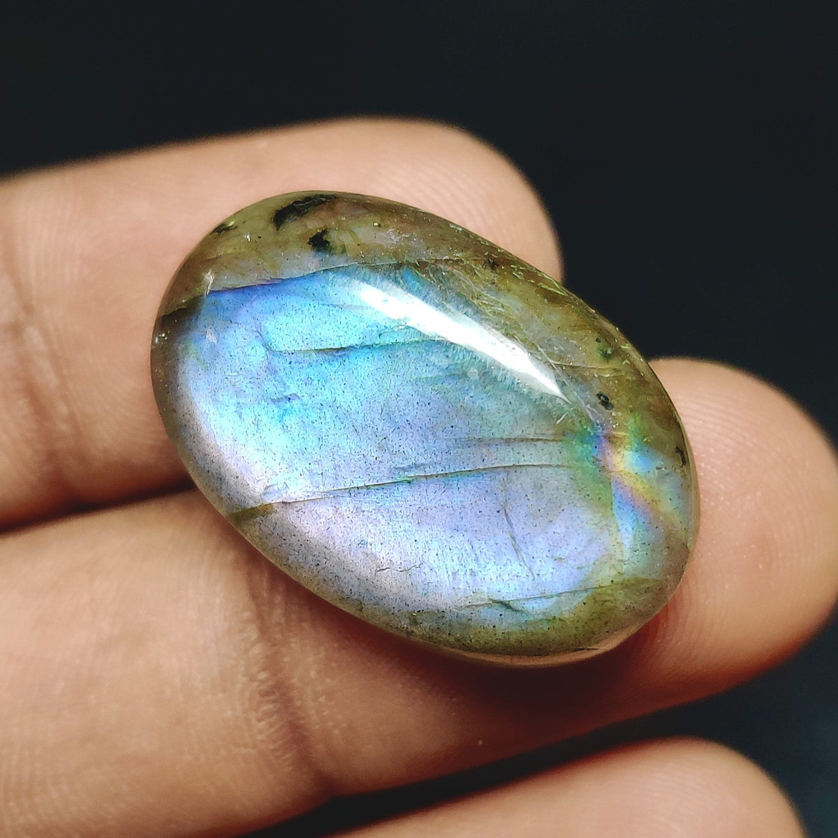 Cabochons4sale oval labradorite cabochon with translucent multi-colour iridescent flash held between fingers