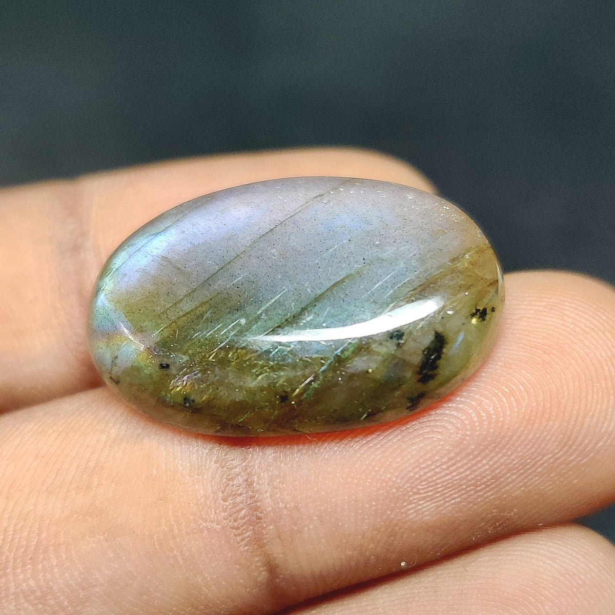 Cabochons4sale oval labradorite cabochon with translucent multi-colour iridescent sheen held between fingers