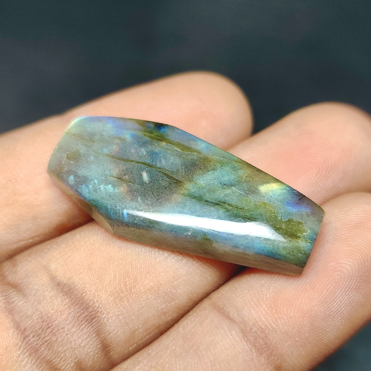 Cabochons4sale fancy translucent labradorite gemstone with iridescent blue and green flashes held in a hand
