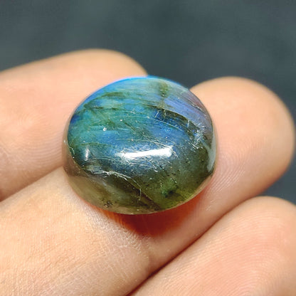 Cabochons4sale round translucent labradorite gemstone with blue iridescent flash held between fingers
