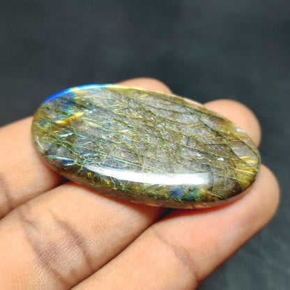 Cabochons4sale oval labradorite cabochon with translucent multi-colour flashes held in a hand