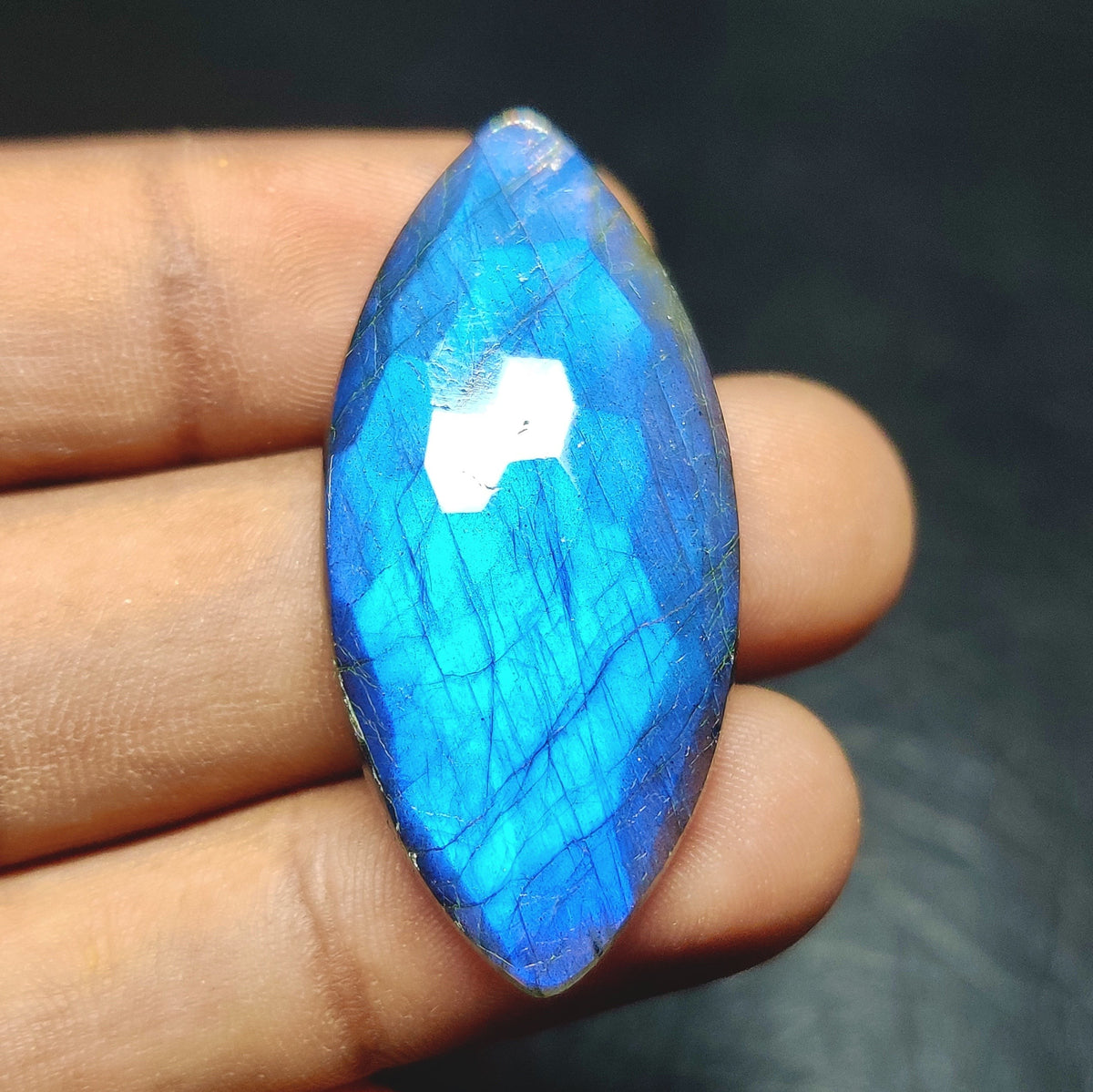 Cabochons4sale marquise cut labradorite gemstone with a translucent blue honeycomb pattern held in fingers