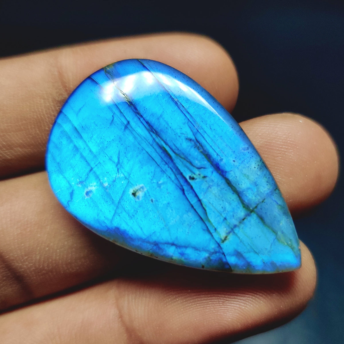 Cabochons4sale pear-shaped translucent labradorite gemstone with vibrant blue flash held in hand