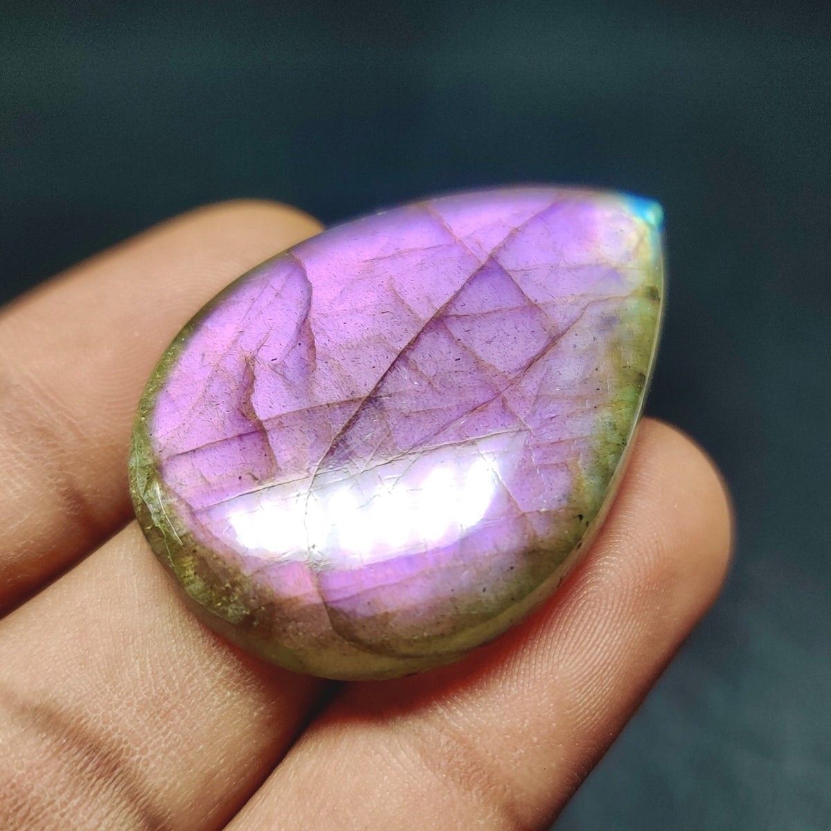 Cabochons4sale pear-shaped translucent labradorite gemstone with a vibrant purple flash held in a hand