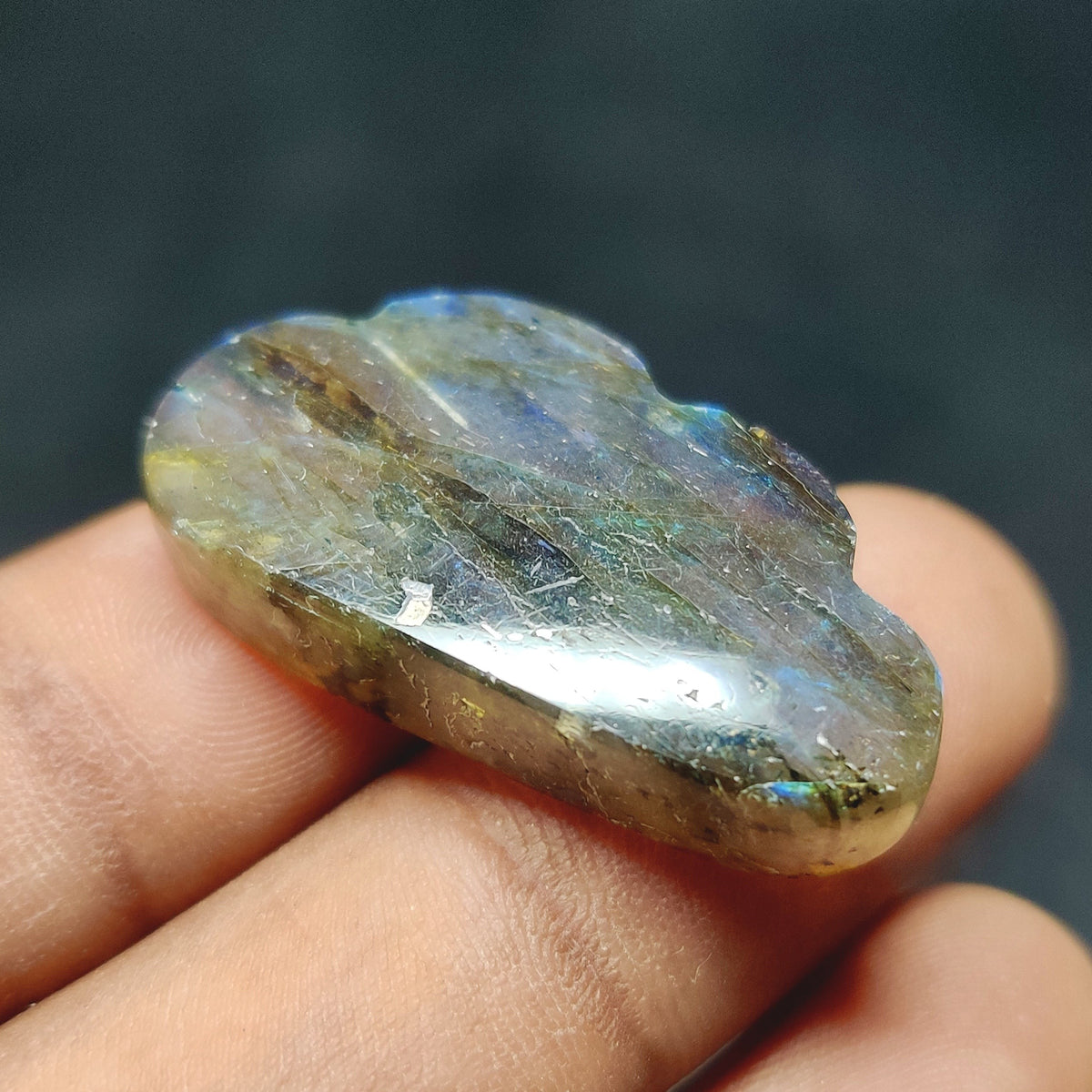 Cabochons4sale translucent fancy labradorite cabochon with blue iridescent flashes held between fingers