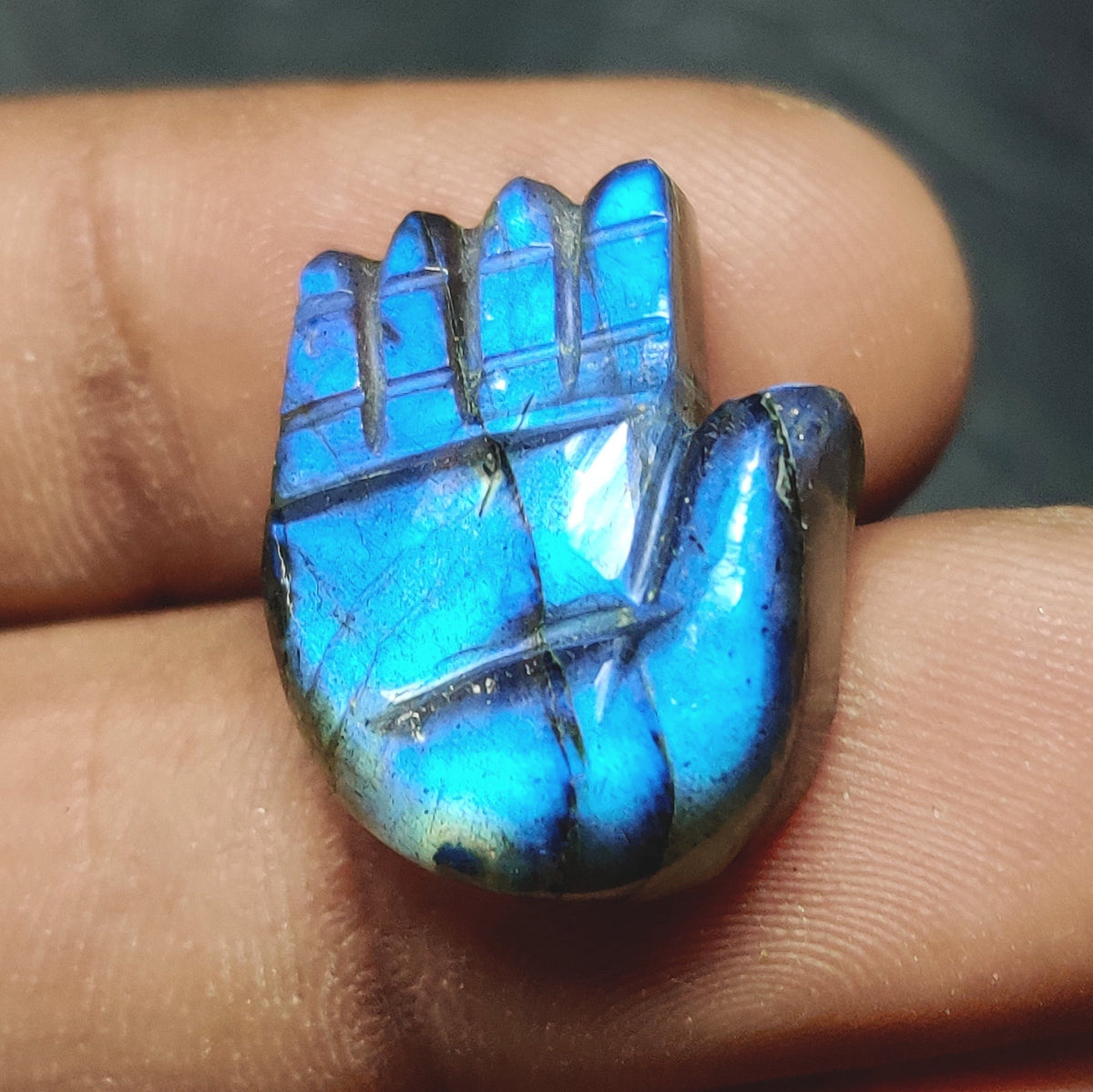 Cabochons4sale translucent blue labradorite gemstone carved into a hamsa hand shape held between fingers