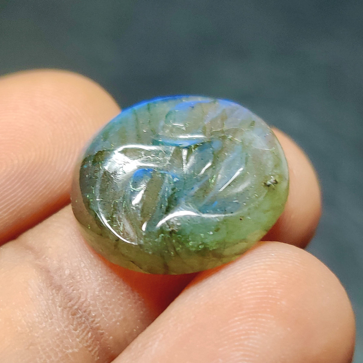 Cabochons4sale translucent blue labradorite gemstone carving held between fingers showing natural iridescent sheen