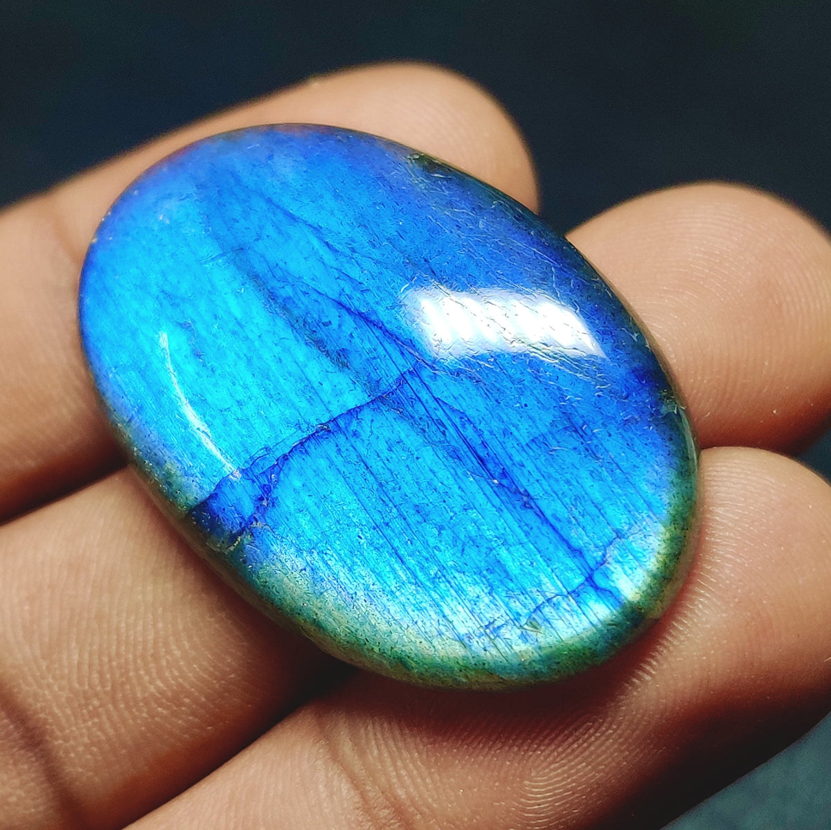 Cabochons4sale oval labradorite gemstone with vibrant blue flash and translucent finish held in hand
