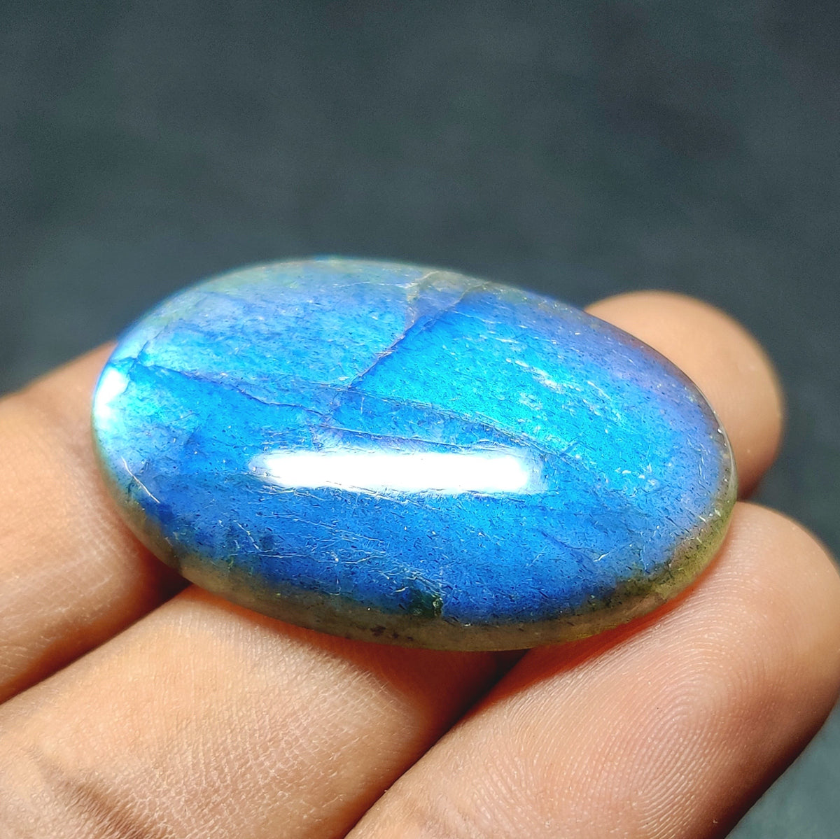 Cabochons4sale oval labradorite cabochon with vibrant blue flash and translucent finish held in hand