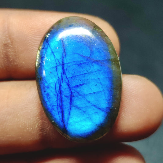 Cabochons4sale oval labradorite gemstone with vibrant blue flash and translucent clarity held between fingers