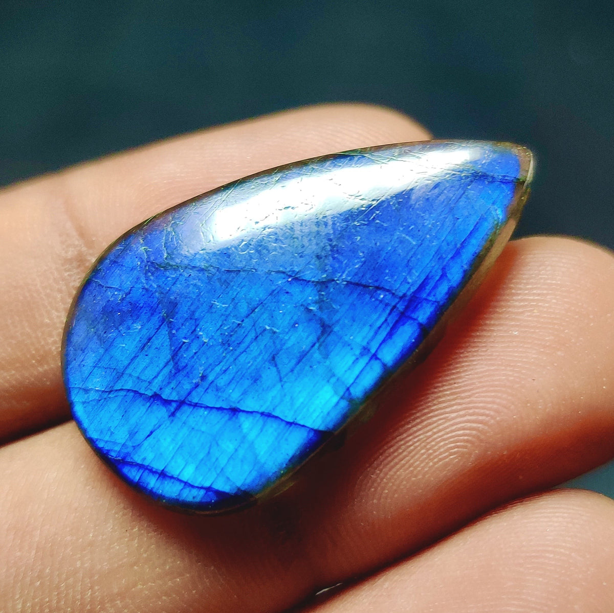 Cabochons4sale pear-shaped translucent labradorite gemstone with vibrant blue flash held in a hand