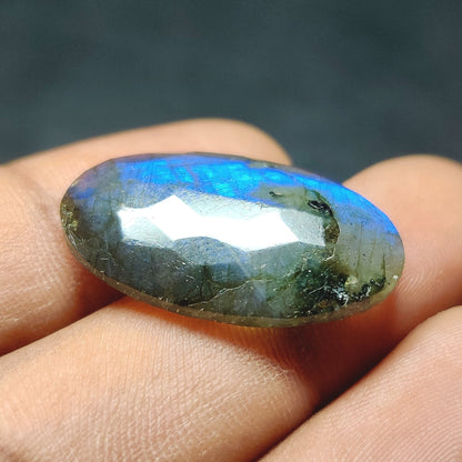 Cabochons4sale oval labradorite gemstone with blue iridescent flash held between fingers