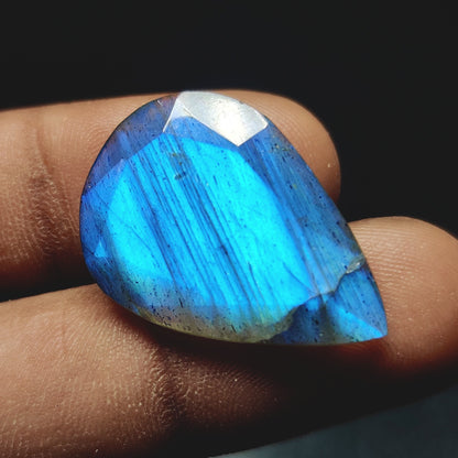 Cabochons4sale pear-shaped translucent labradorite gemstone with vibrant blue flash held between fingers