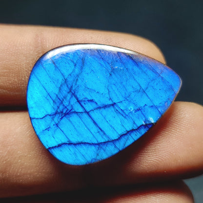 Cabochons4sale pear-shaped translucent blue labradorite gemstone cabochon held between fingers