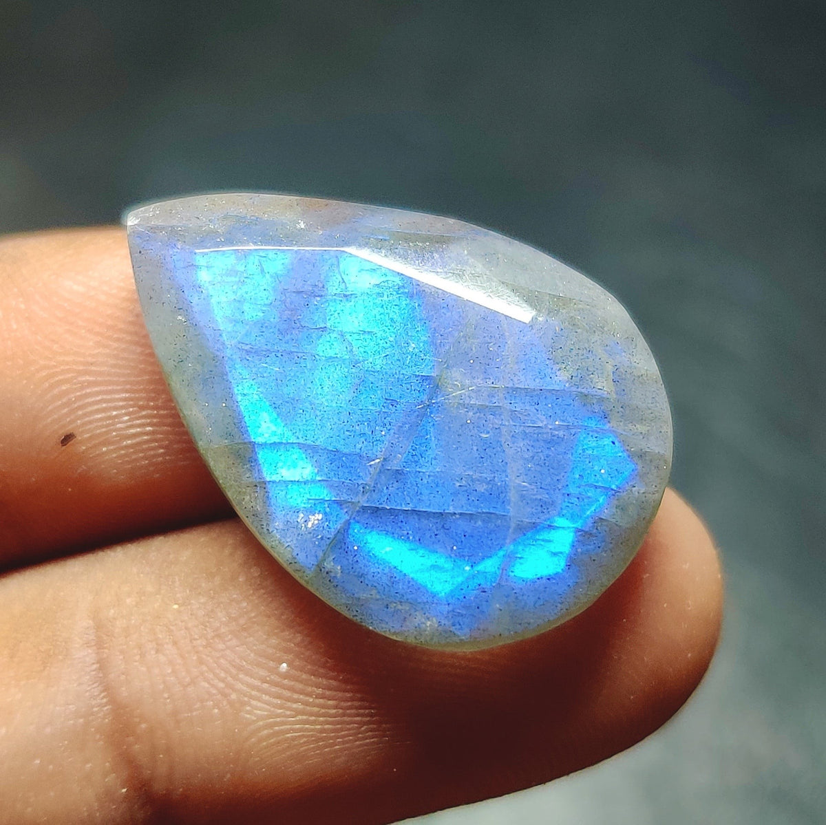 Cabochons4sale pear-shaped faceted labradorite gemstone with vibrant blue flash held between fingers