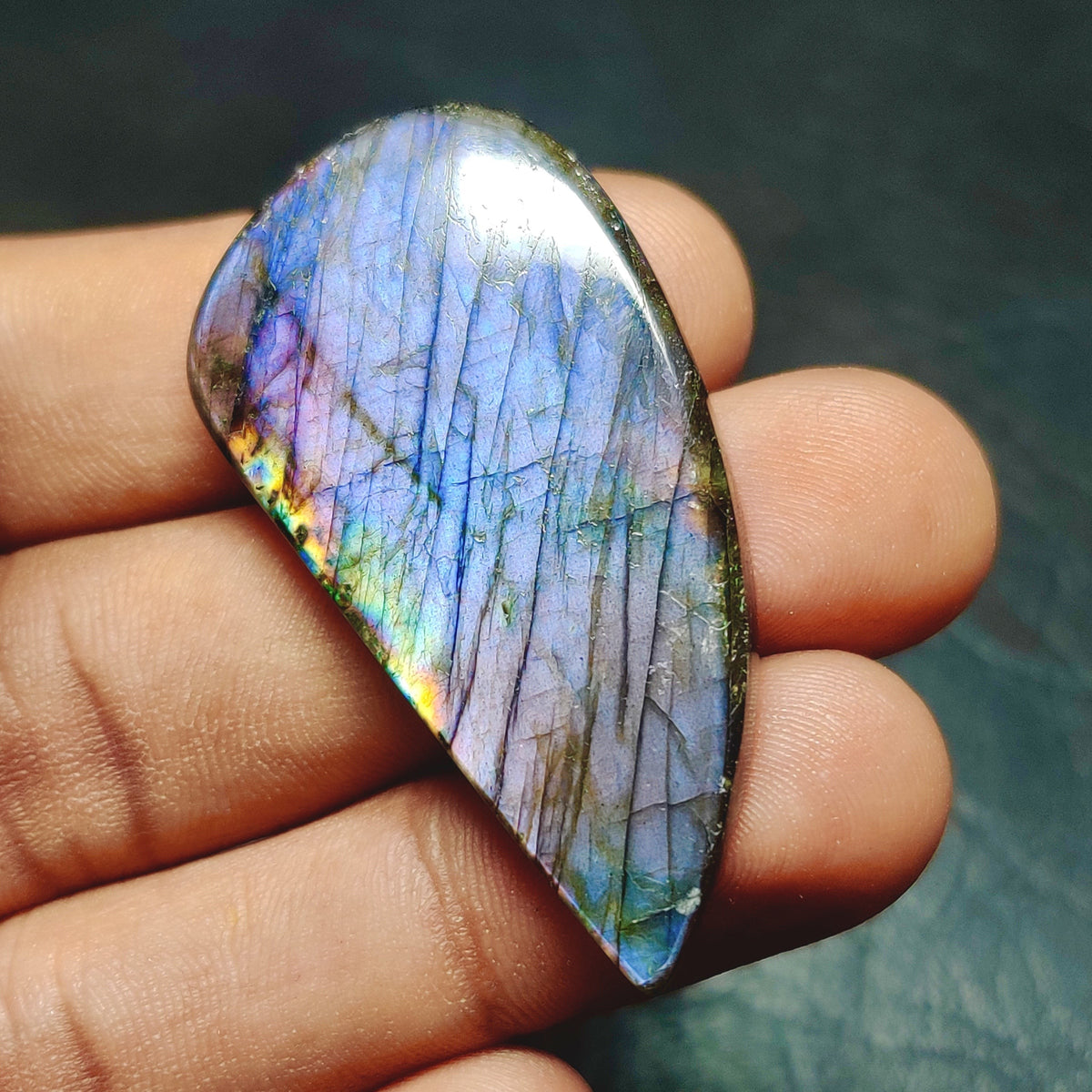 Cabochons4sale pear-shaped labradorite cabochon with iridescent blue and purple flashes held in a hand