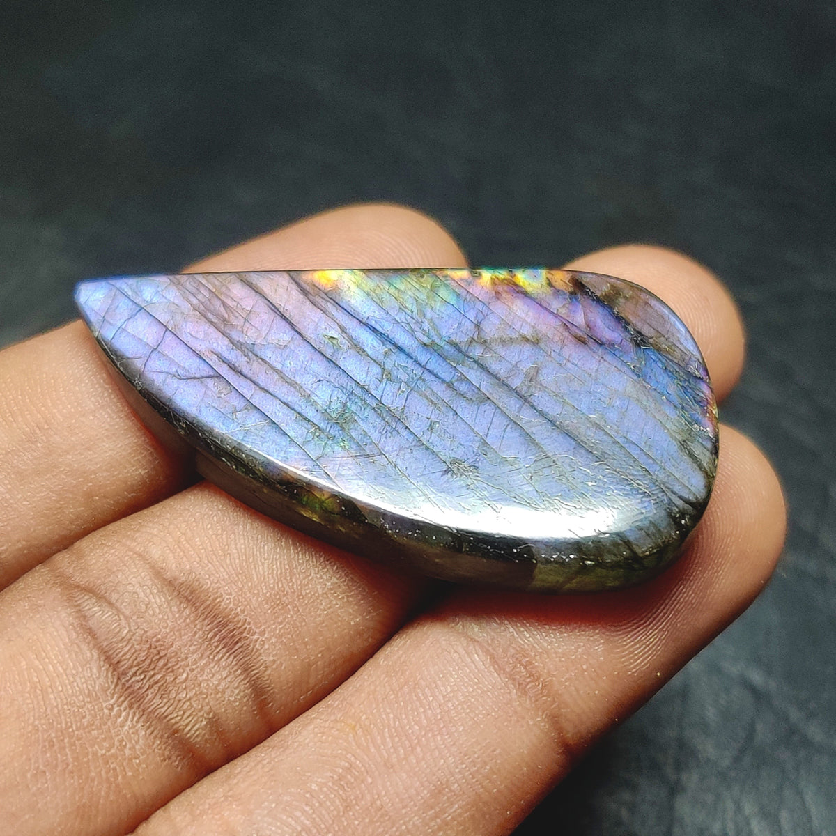 Cabochons4sale translucent pear-shaped labradorite gemstone with blue and purple iridescent flash held in hand