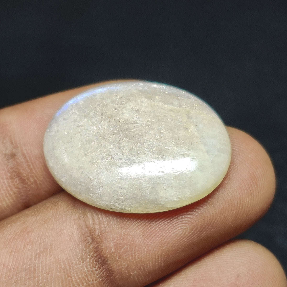 Cabochons4sale natural white translucent oval moonstone cabochon held between fingers