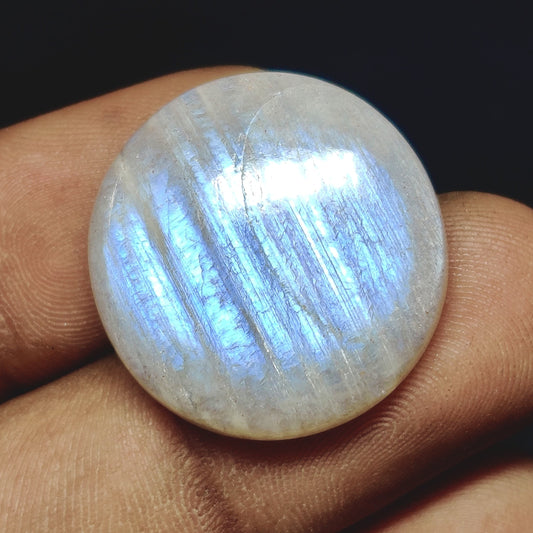 Cabochons4sale round translucent white moonstone cabochon with blue adularescence held between fingers