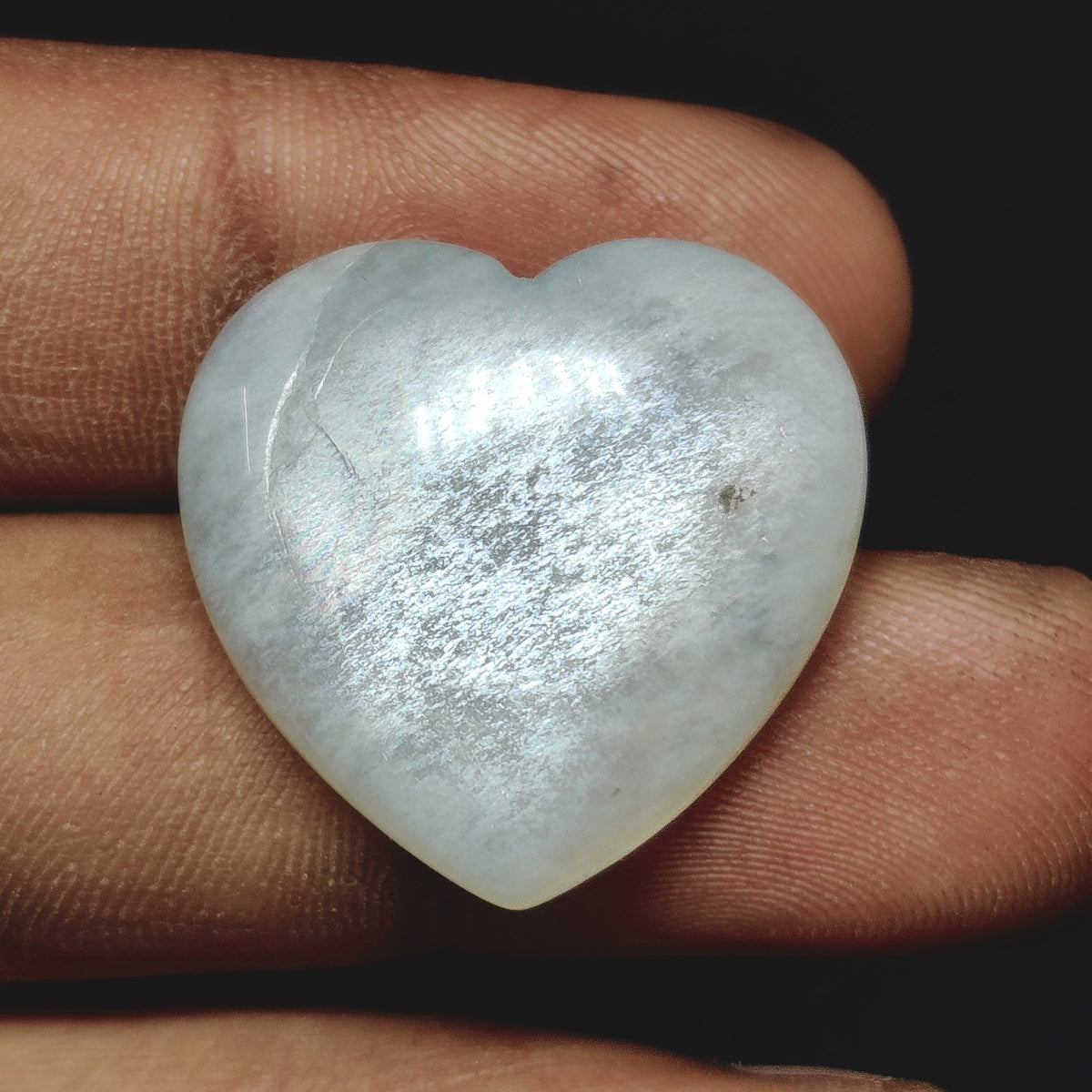 Cabochons4sale translucent white moonstone heart carving held between fingers showing natural gemstone shimmer