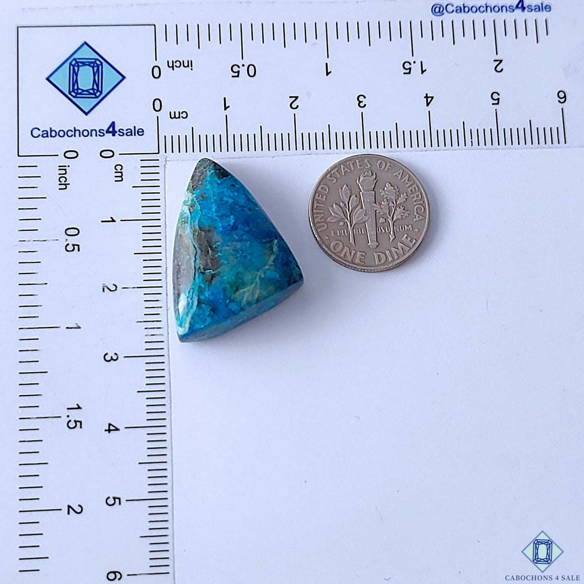 Cabochons4sale fancy triangle-shaped Quantum Quattro cabochon with vibrant blue and green patterns next to a dime.