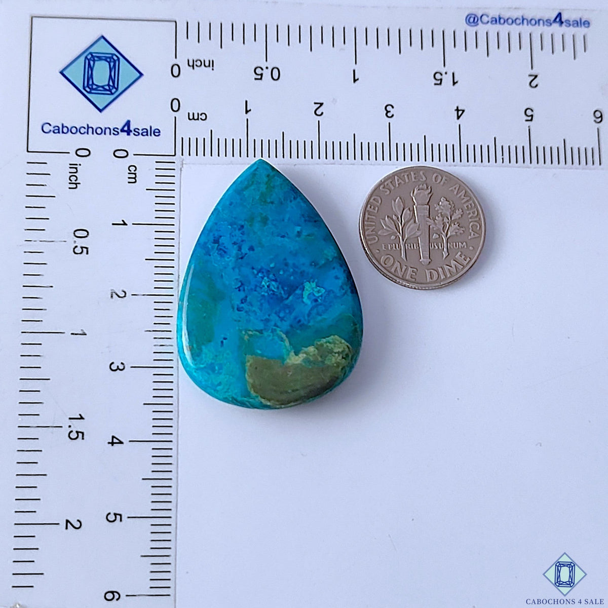 Cabochons4sale pear-shaped Quantum Quattro cabochon with vibrant blue and green patterns on a measuring scale.