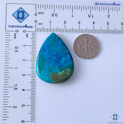 Cabochons4sale pear-shaped Quantum Quattro cabochon with vibrant blue and green patterns on a measuring scale.