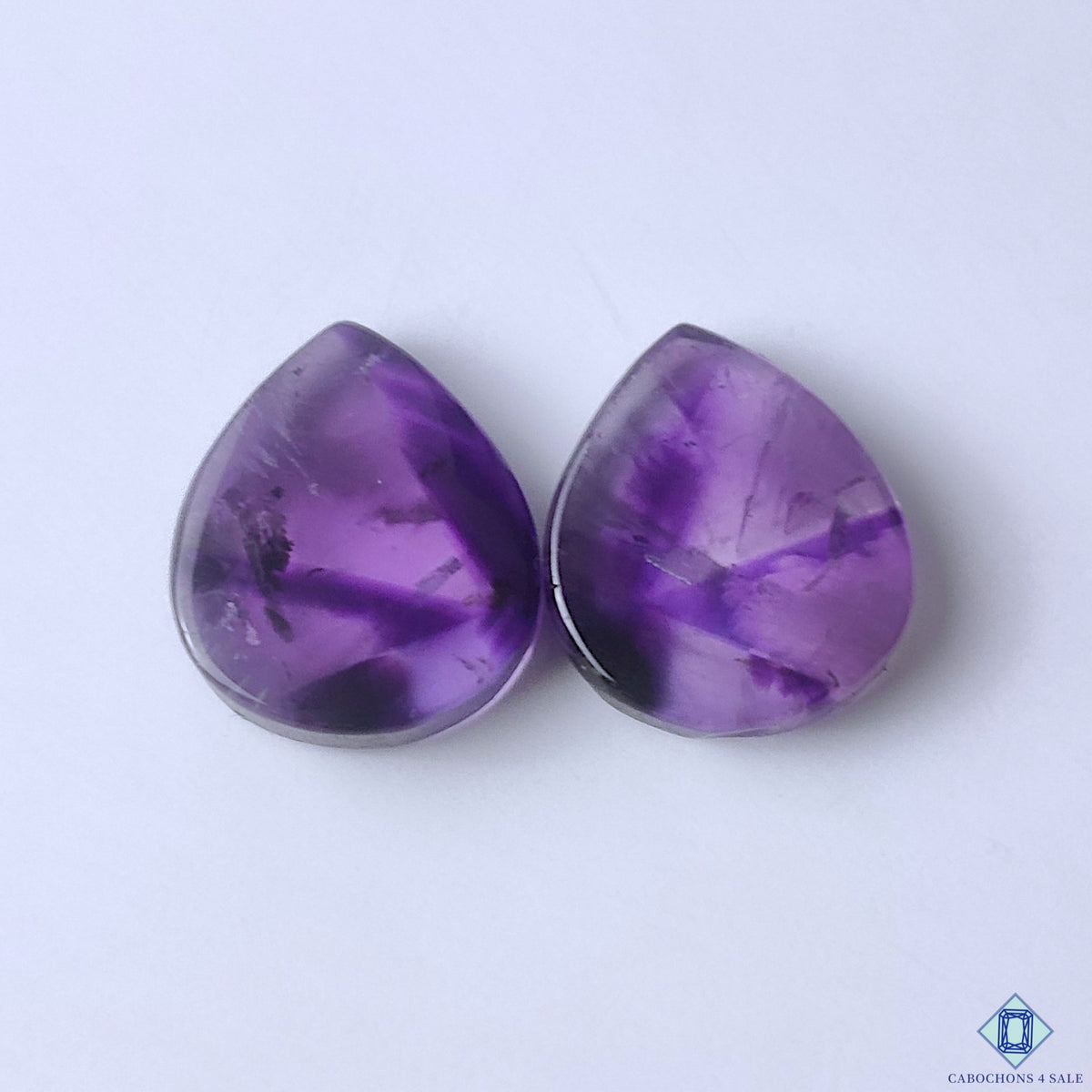 cabochons4sale, natural purple amethyst pear cabochons with rich violet color, subtle crystal texture and polished gemstone surfaces held between fingers