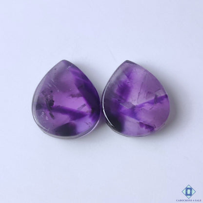 cabochons4sale, natural purple amethyst pear cabochons with rich violet color, subtle crystal texture and polished gemstone surfaces held between fingers