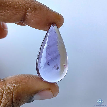 cabochons4sale, natural ametrine pear cabochons in purple tones with subtle quartz color variation, crystalline depth and smooth polished surfaces held between fingers