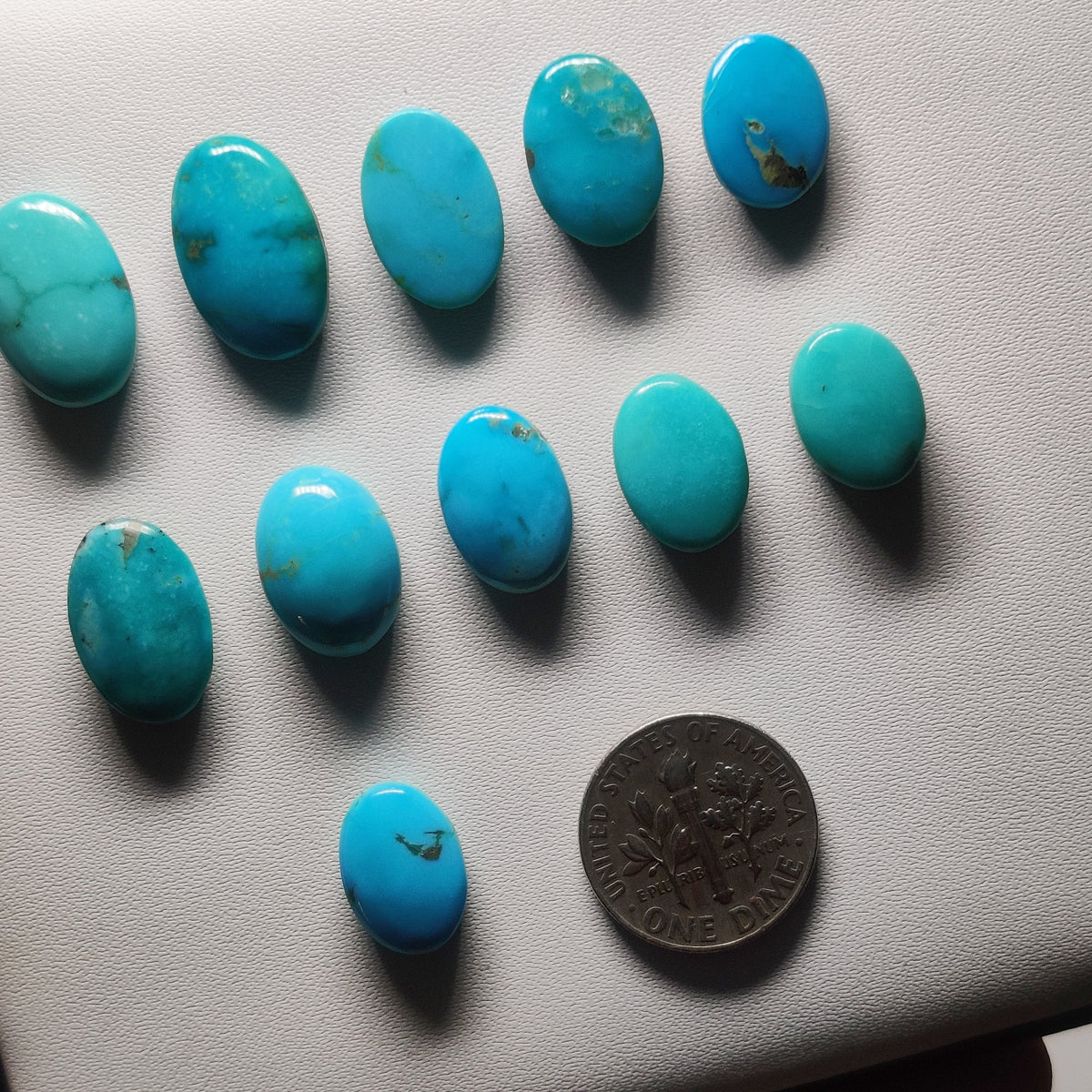 Cabochons4sale natural Arizona turquoise cabochons in blue-green with matrix patterns, displayed next to a US dime.