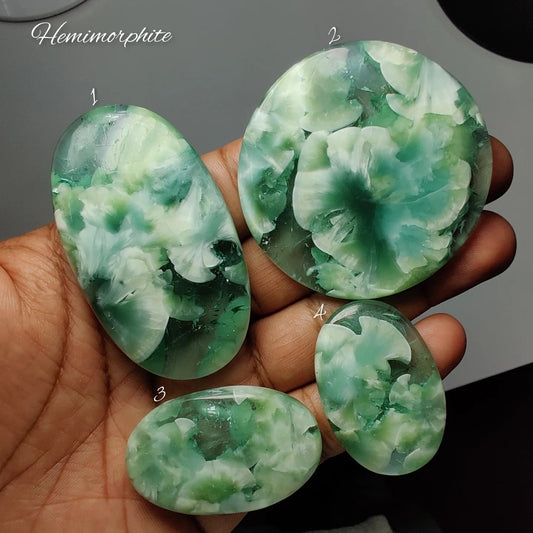 Cabochons4sale natural hemimorphite gemstones with blue-green floral patterns held in a hand for jewelry making