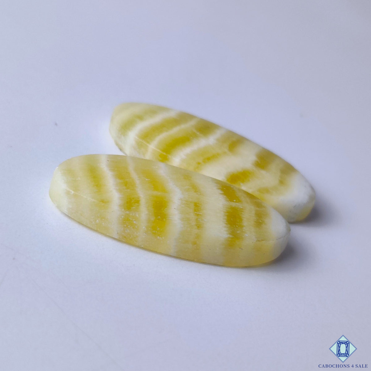 cabochons4sale, vibrant yellow calcite oval cabochons showcasing a naturally glowing appearance, crystalline character and refined polished finish held between fingers