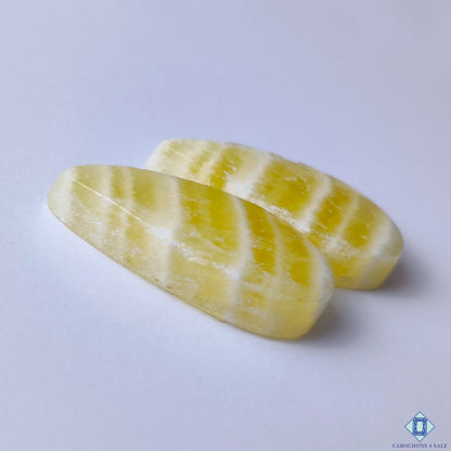 cabochons4sale, sunny yellow calcite pear cabochons showcasing natural crystalline character, glowing color and elegant polished gemstone finish held between fingers