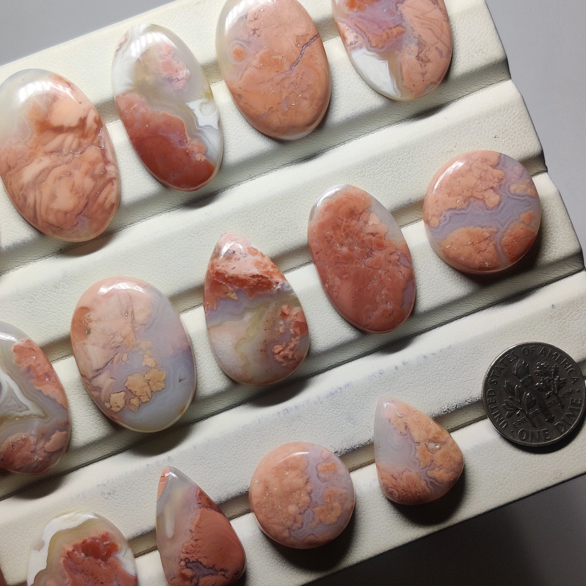 Cabochons4sale polished cherry blossom agate cabochons in various shapes with pink and cream floral patterns.