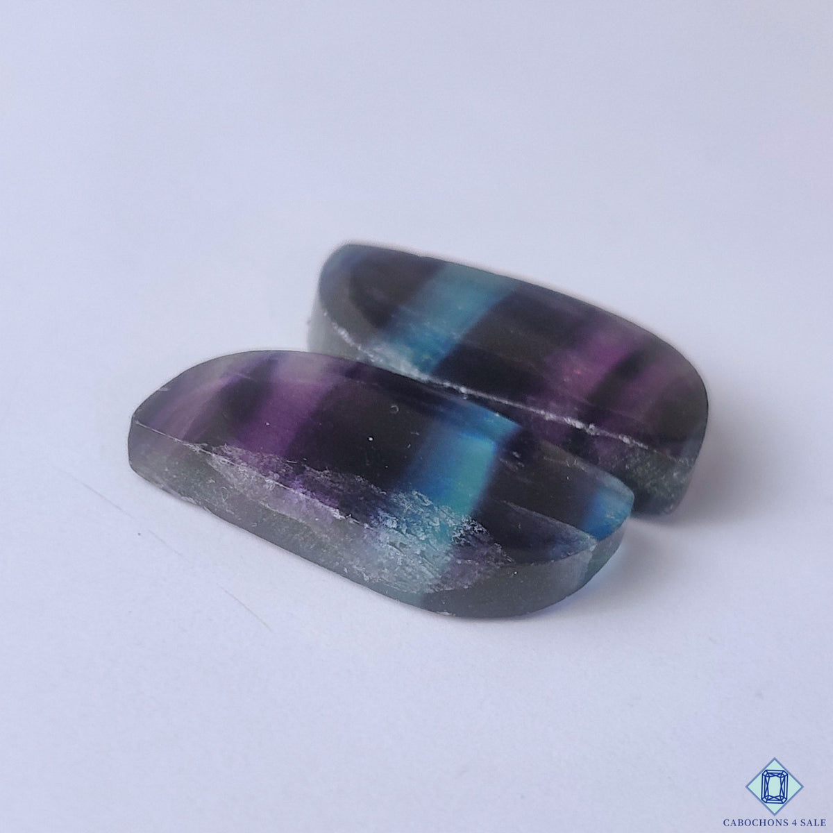cabochons4sale, rainbow fluorite fancy cabochons showcasing vivid green, violet and blue hues with elegant mineral zoning and smooth gemstone polish held between fingers