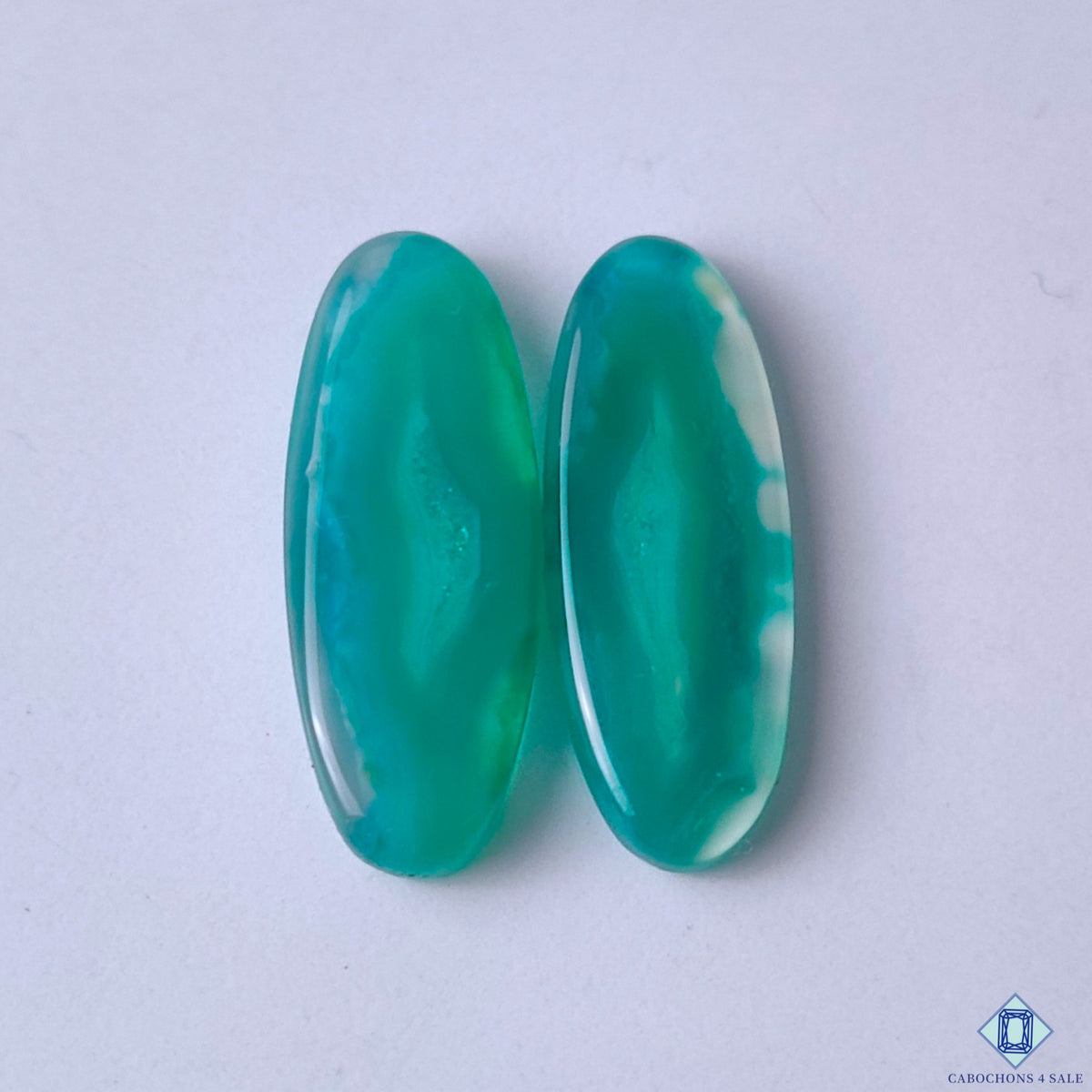 cabochons4sale, green banded agate oval cabochons in green and white tones with graceful mineral bands and natural layered patterns held between fingers
