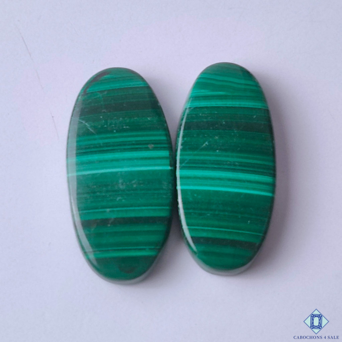 cabochons4sale, green malachite oval cabochons with striking swirling bands, layered mineral patterns and rich natural color held between fingers