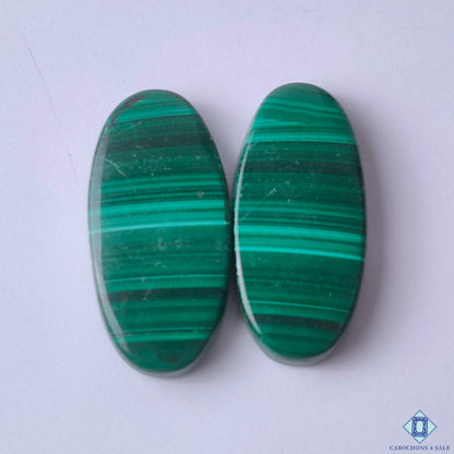 cabochons4sale, green malachite oval cabochons with striking swirling bands, layered mineral patterns and rich natural color held between fingers