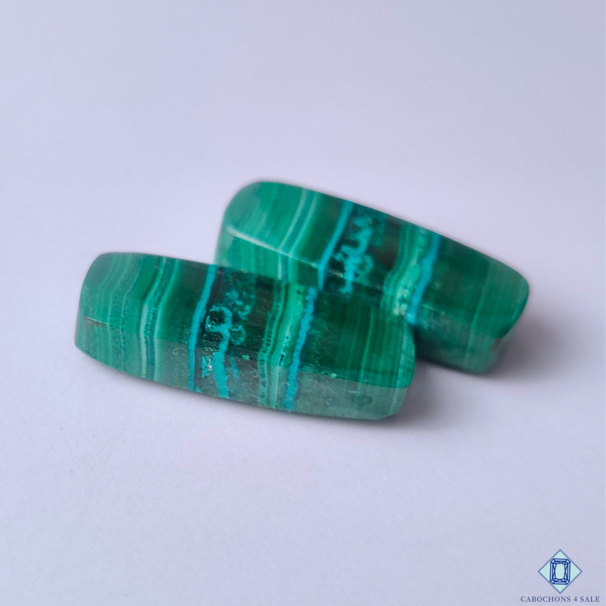 cabochons4sale, polished green malachite rectangular cabochons showcasing striking concentric markings, rich color variation and natural mineral character held between fingers