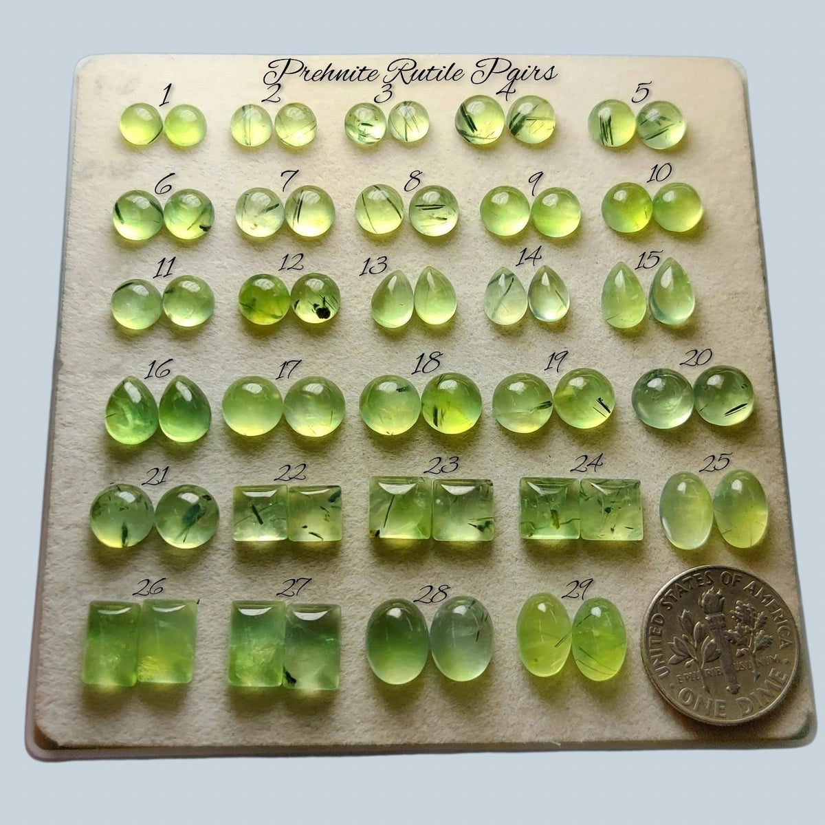 Cabochons4sale collection of polished mint green prehnite rutile quartz gemstones with golden needles on a display tray