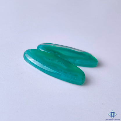 cabochons4sale, oval green banded agate cabochons featuring soft white layers, organic curved markings and a smooth polished gemstone surface held between fingers