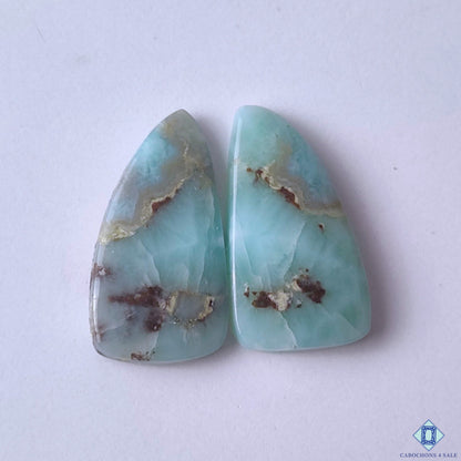 cabochons4sale, fancy blue and white larimar cabochons with ocean-like patterns, aqua hues and natural gemstone texture held between fingers