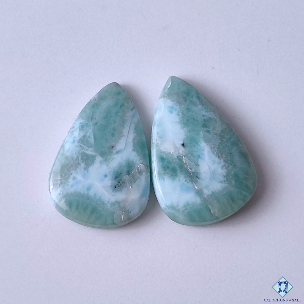 cabochons4sale, aqua blue and white larimar pear cabochons with soft ocean-inspired patterns, natural mineral details and polished gemstone surfaces held between fingers