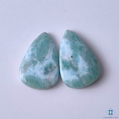 cabochons4sale, aqua blue and white larimar pear cabochons with soft ocean-inspired patterns, natural mineral details and polished gemstone surfaces held between fingers