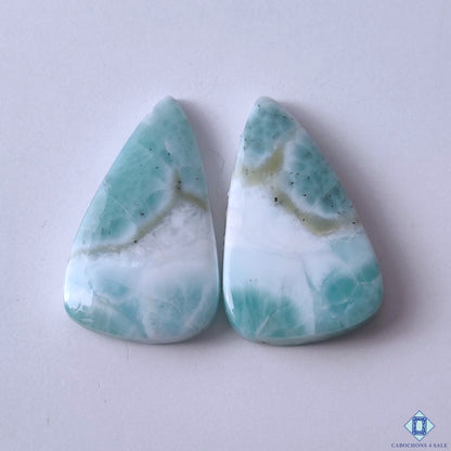 cabochons4sale, blue and white larimar pear cabochons with dreamy seascape patterns, aqua tones and natural gemstone texture held between fingers