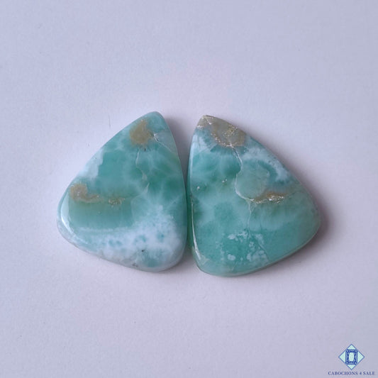 cabochons4sale, blue and white larimar pear cabochons with soft aqua tones, natural cloudy patterns and polished gemstone surfaces held between fingers