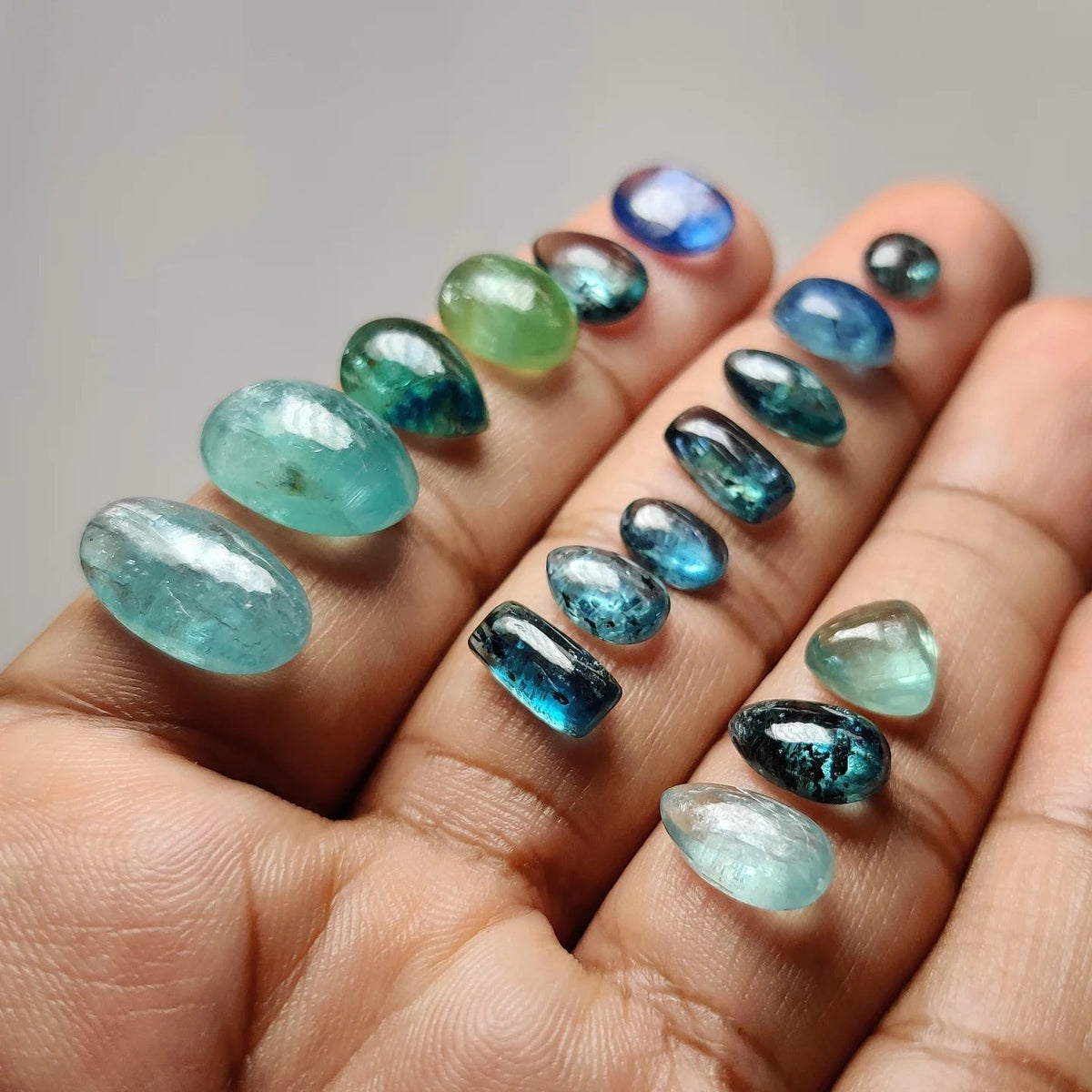 Cabochons4sale collection of loose blue and green kyanite gemstones held in a hand for jewelry making