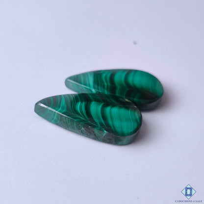 cabochons4sale, polished emerald green malachite pear cabochons showcasing layered circular markings, deep mineral tones and smooth gemstone texture held between fingers